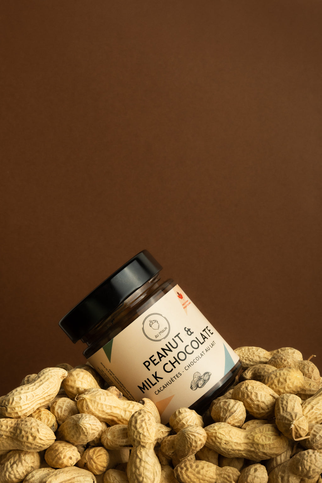 Aupralin peanut milk chocolate spread diagonally placed in peanuts