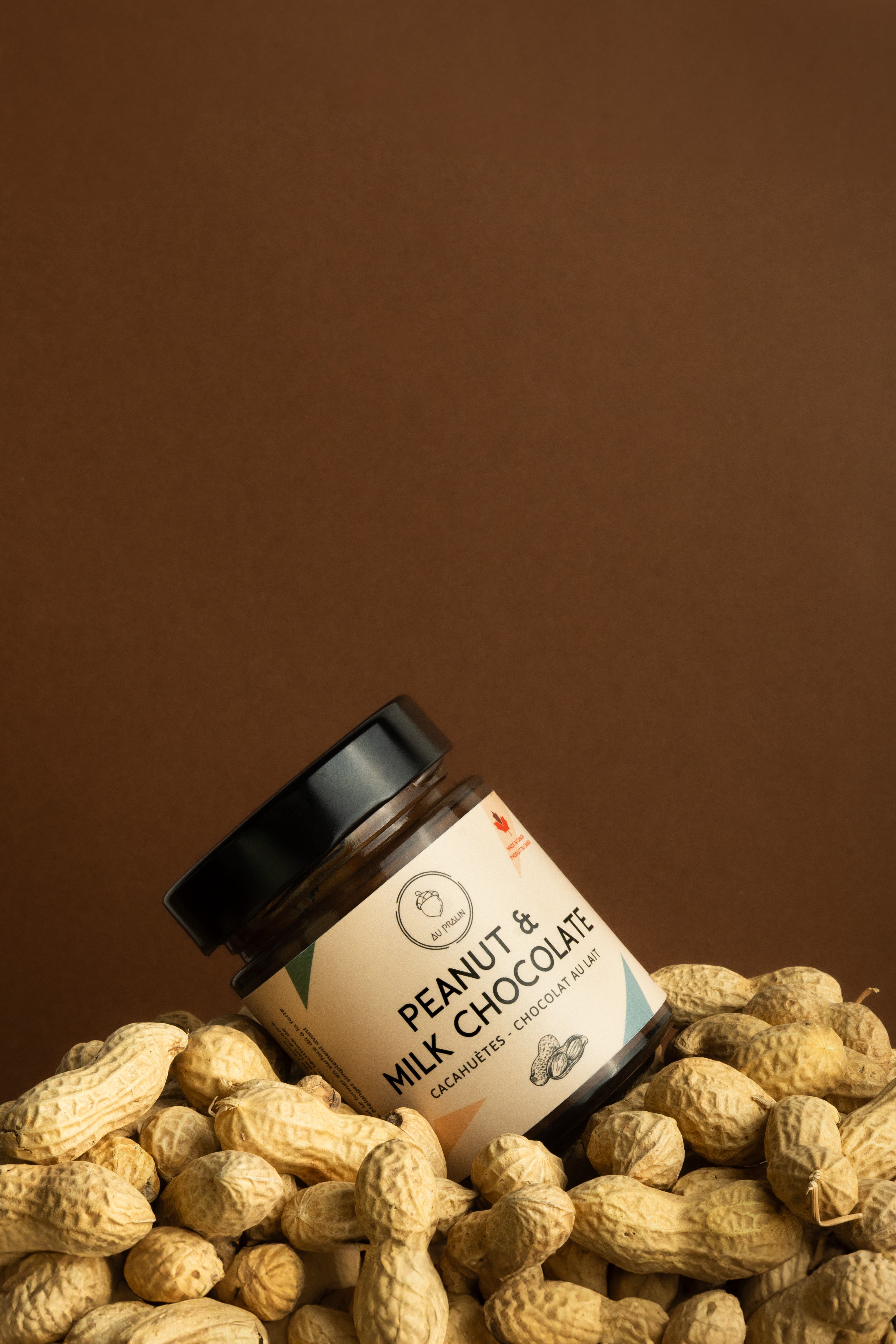 Aupralin peanut milk chocolate spread diagonally placed in peanuts